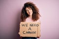 Young beautiful activist woman with curly hair and piercing protesting asking for a change with a happy face standing and smiling