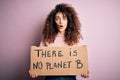 Young beautiful activist woman with curly hair and piercing protesting asking for change planet scared in shock with a surprise