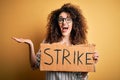 Young beautiful activist woman with curly hair and piercing protesting in strike holding poster very happy and excited, winner