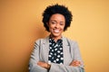 Young beautiful African American afro businesswoman with curly hair wearing jacket happy face smiling with crossed arms looking at Royalty Free Stock Photo