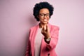 Young beautiful African American afro businesswoman with curly hair wearing pink jacket Beckoning come here gesture with hand