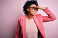 Young beautiful African American afro businesswoman with curly hair wearing pink jacket very happy and smiling looking far away Royalty Free Stock Photo