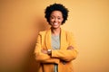 Young beautiful African American afro businesswoman with curly hair wearing yellow jacket happy face smiling with crossed arms Royalty Free Stock Photo