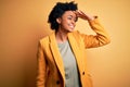 Young beautiful African American afro businesswoman with curly hair wearing yellow jacket very happy and smiling looking far away Royalty Free Stock Photo