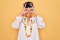 Young beautiful african american afro hippie woman wearing sunglasses and accessories doing ok gesture like binoculars sticking