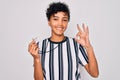 Young beautiful african american afro referee woman wearing striped uniform using whistle doing ok sign with fingers, excellent