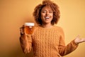 Young beautiful African American afro woman with curly hair drinking jar of beer very happy and excited, winner expression Royalty Free Stock Photo