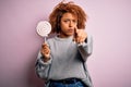 Young beautiful African American afro woman with curly hair eating sweet candy pointing with finger to the camera and to you, hand Royalty Free Stock Photo