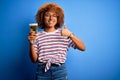 Young beautiful African American afro woman with curly hair on vacation drinking glass of beer happy with big smile doing ok sign, Royalty Free Stock Photo