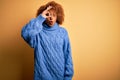 Young beautiful African American afro woman with curly hair wearing blue turtleneck sweater doing ok gesture shocked with Royalty Free Stock Photo