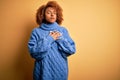 Young beautiful African American afro woman with curly hair wearing blue turtleneck sweater smiling with hands on chest with Royalty Free Stock Photo