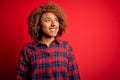 Young beautiful African American afro woman with curly hair wearing casual shirt looking away to side with smile on face, natural Royalty Free Stock Photo