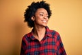 Young beautiful African American afro woman with curly hair wearing casual shirt looking away to side with smile on face, natural Royalty Free Stock Photo