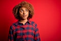 Young beautiful African American afro woman with curly hair wearing casual shirt smiling looking to the side and staring away Royalty Free Stock Photo