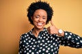 Young beautiful African American afro woman with curly hair wearing casual shirt standing doing happy thumbs up gesture with hand Royalty Free Stock Photo