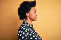 Young beautiful African American afro woman with curly hair wearing casual shirt standing looking to side, relax profile pose with Royalty Free Stock Photo