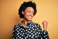 Young beautiful African American afro woman with curly hair wearing casual shirt standing smiling with happy face looking and Royalty Free Stock Photo