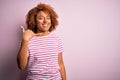 Young beautiful African American afro woman with curly hair wearing casual striped t-shirt smiling doing phone gesture with hand Royalty Free Stock Photo