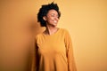 Young beautiful African American afro woman with curly hair wearing casual t-shirt looking away to side with smile on face, Royalty Free Stock Photo