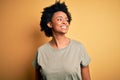 Young beautiful African American afro woman with curly hair wearing casual t-shirt looking away to side with smile on face, Royalty Free Stock Photo