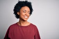 Young beautiful African American afro woman with curly hair wearing casual t-shirt standing looking away to side with smile on Royalty Free Stock Photo