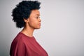 Young beautiful African American afro woman with curly hair wearing casual t-shirt standing looking to side, relax profile pose Royalty Free Stock Photo