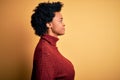 Young beautiful African American afro woman with curly hair wearing casual turtleneck sweater looking to side, relax profile pose