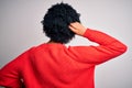 Young beautiful African American afro woman with curly hair wearing red casual sweater Backwards thinking about doubt with hand on Royalty Free Stock Photo