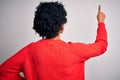 Young beautiful African American afro woman with curly hair wearing red casual sweater Posing backwards pointing ahead with finger Royalty Free Stock Photo