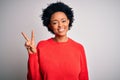 Young beautiful African American afro woman with curly hair wearing red casual sweater smiling looking to the camera showing Royalty Free Stock Photo