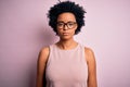 Young beautiful African American afro woman with curly hair wearing t-shirt and glasses with serious expression on face Royalty Free Stock Photo