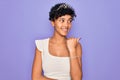 Young beautiful african american afro woman wearing tiara crown over purple background smiling with happy face looking and Royalty Free Stock Photo