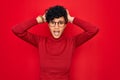 Young beautiful african american afro woman wearing turtleneck sweater and glasses Crazy and scared with hands on head, afraid and Royalty Free Stock Photo