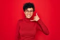 Young beautiful african american afro woman wearing turtleneck sweater and glasses smiling doing phone gesture with hand and Royalty Free Stock Photo