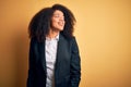 Young beautiful african american business woman with afro hair wearing elegant jacket looking away to side with smile on face, Royalty Free Stock Photo