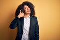 Young beautiful african american business woman with afro hair wearing elegant jacket smiling doing phone gesture with hand and Royalty Free Stock Photo