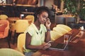 Young beautiful African-American business woman talking on the phone while working in a cafe Royalty Free Stock Photo