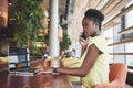 Young beautiful African-American business woman talking on the phone while working in a cafe Royalty Free Stock Photo