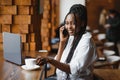 Young beautiful African-American business woman talking on the phone while working in a cafe Royalty Free Stock Photo