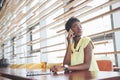 Young beautiful African-American business woman talking on the phone while working in a cafe Royalty Free Stock Photo