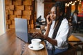 Young beautiful African-American business woman talking on the phone while working in a cafe Royalty Free Stock Photo