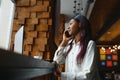 Young beautiful African-American business woman talking on the phone while working in a cafe Royalty Free Stock Photo