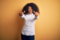 Young beautiful african american elegant woman with afro hair standing over yellow background approving doing positive gesture Royalty Free Stock Photo