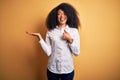 Young beautiful african american elegant woman with afro hair standing over yellow background Showing palm hand and doing ok Royalty Free Stock Photo