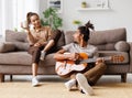 Young beautiful african american family couple playing acoustic guitar at home Royalty Free Stock Photo