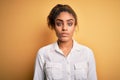 Young beautiful african american girl wearing casual shirt standing over yellow background Relaxed with serious expression on face Royalty Free Stock Photo