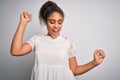 Young beautiful african american girl wearing casual t-shirt standing over white background Dancing happy and cheerful, smiling Royalty Free Stock Photo
