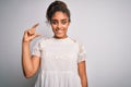 Young beautiful african american girl wearing casual t-shirt standing over white background smiling and confident gesturing with Royalty Free Stock Photo
