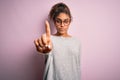 Young beautiful african american girl wearing sweater and glasses over pink background Pointing with finger up and angry Royalty Free Stock Photo