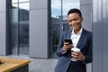 Young beautiful african american student with short hair, uses mobile phone happy and smiling walking in the city Royalty Free Stock Photo